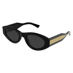 Black Gucci sunglasses with oval dark lenses and black glossy frame, gold patterned arms on the sides.