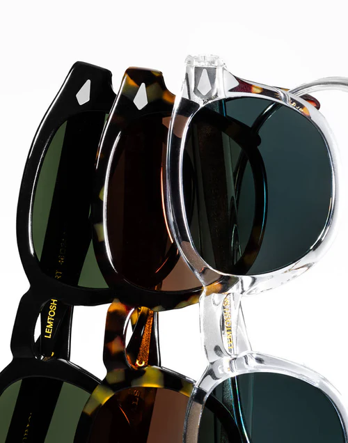 Multiple sunglasses overlapping on a white background, featuring black, tortoiseshell, and clear frames with mirrored lenses