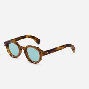 Tortoiseshell sunglasses with round blue lenses resting on a white background, stylish fashion eyewear.