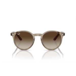 Ray-Ban round sunglasses with a translucent beige frame and brown gradient lenses, reflecting on a white surface.